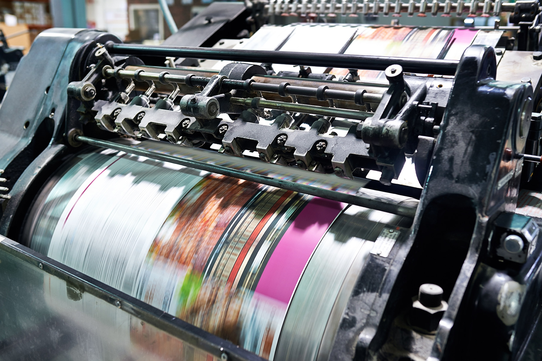 An industrial printing press printing multi-colored magazines