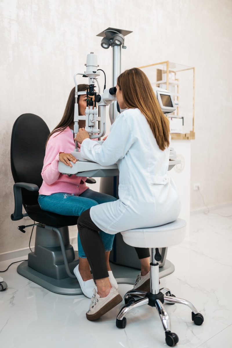 Female optometrist checking patient's vision at eye clinic. Healthcare and medical concept.