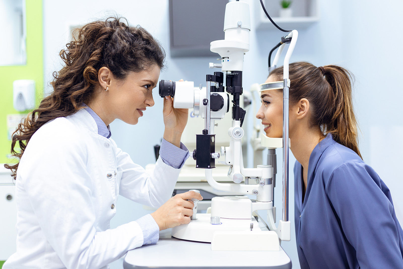 Eye doctor with female patient during an examination in modern clinic. Ophthalmologist is using special medical equipment for eye health saving and improving
