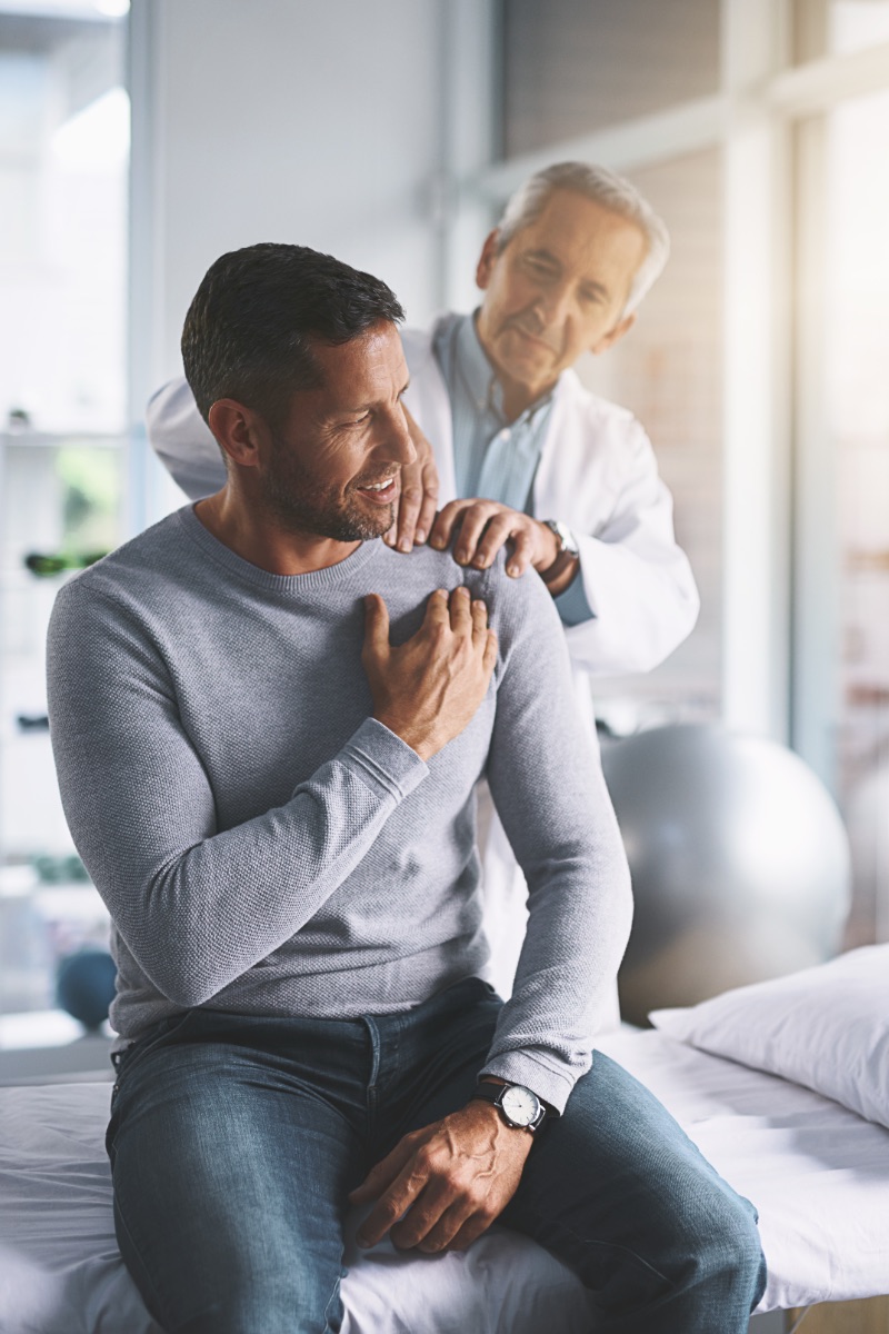 Elderly doctor, man and patient with shoulder pain for physical therapy, healthcare or body recovery. Orthopedic, physician and medical expert for arm consultation with examination, advice or healing