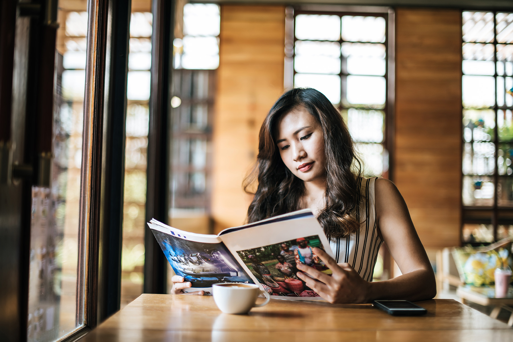 A woman reading a magazine at a cafe